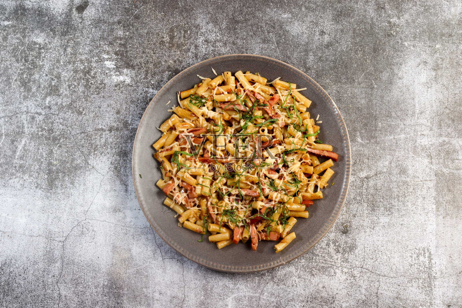 自制的通心粉配火腿和奶酪，放在圆形盘子里，背景是黑色的。俯视图，平面布局照片摄影图片