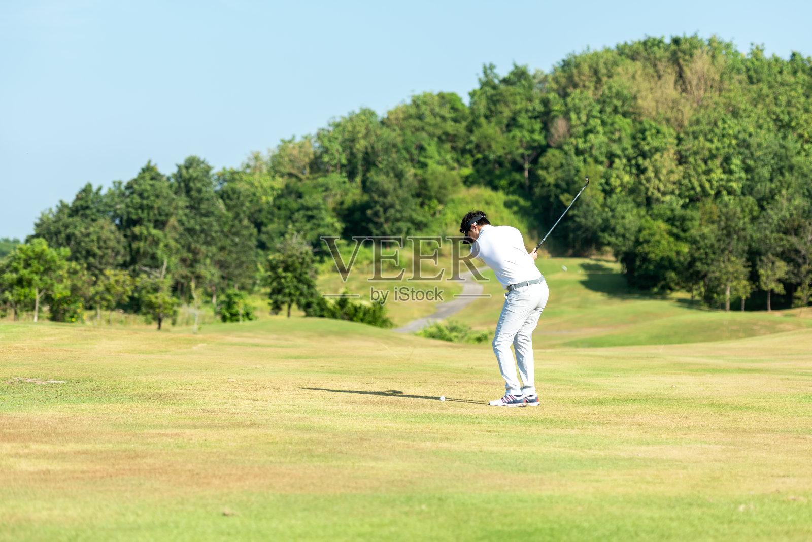 Golfer sport course golf ball fairway.  People lifestyle man playing game and swing golf tee off on the green grass.照片摄影图片
