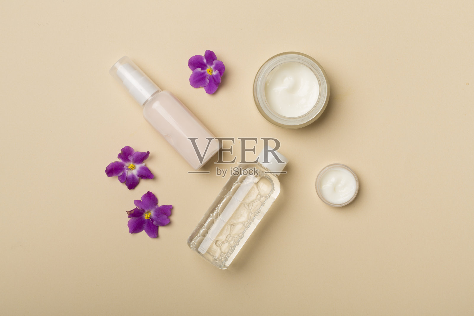 化妆品瓶子和罐子与花的颜色背景，俯视图照片摄影图片