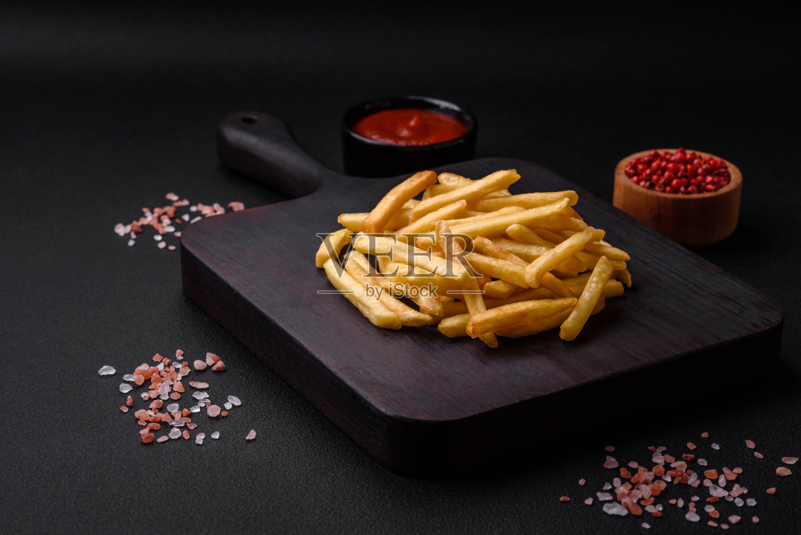美味酥脆的薯条，加上盐和香料，背景是深色的混凝土照片摄影图片