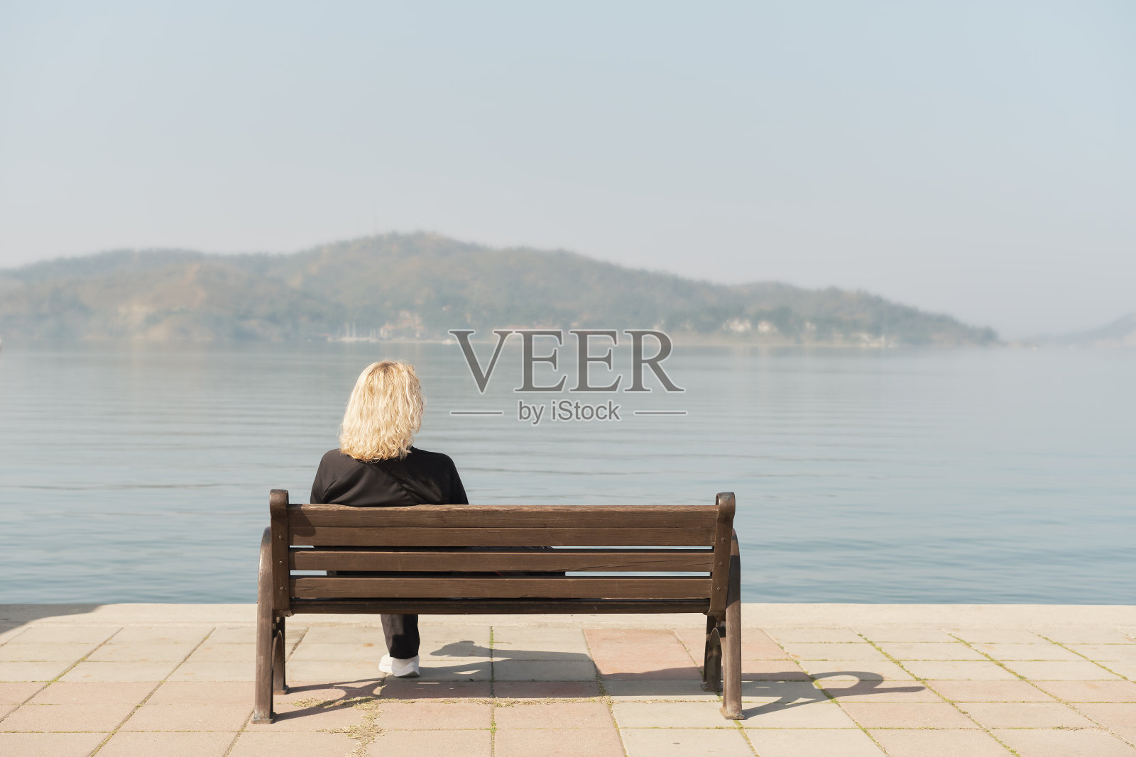 美丽的成年女子在散步后坐在长凳上，看着大海和蓝天，文字想法的空间为背景照片摄影图片