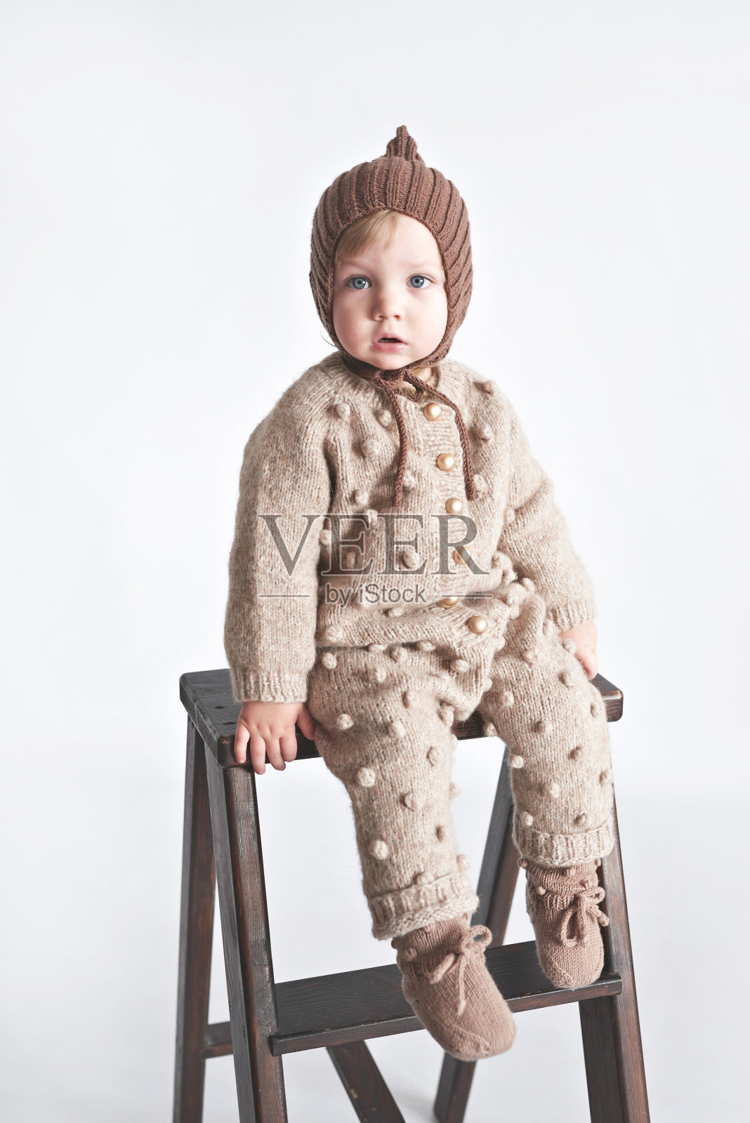 小男孩穿着针织套装，戴着帽子照片摄影图片