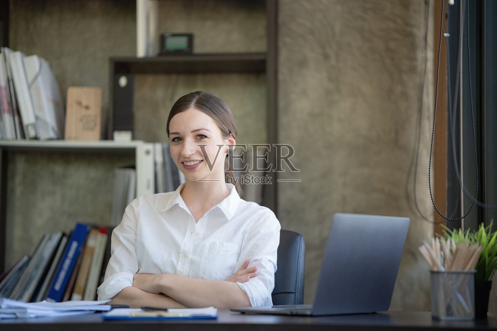 女企业家坐在办公室的办公桌前，双手交叉对着镜头微笑照片摄影图片