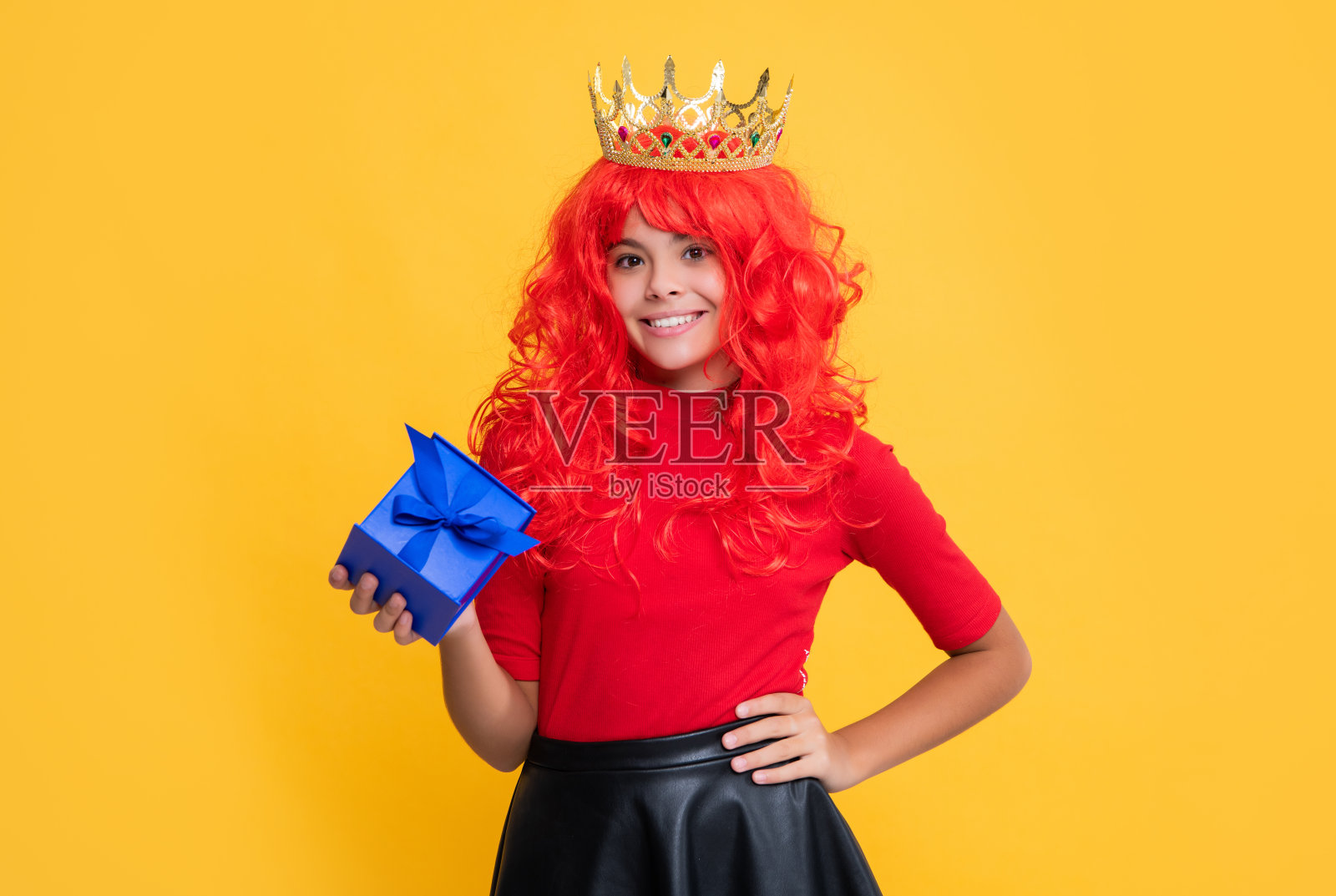 微笑的女孩在皇冠上的礼物盒在黄色的背景照片摄影图片