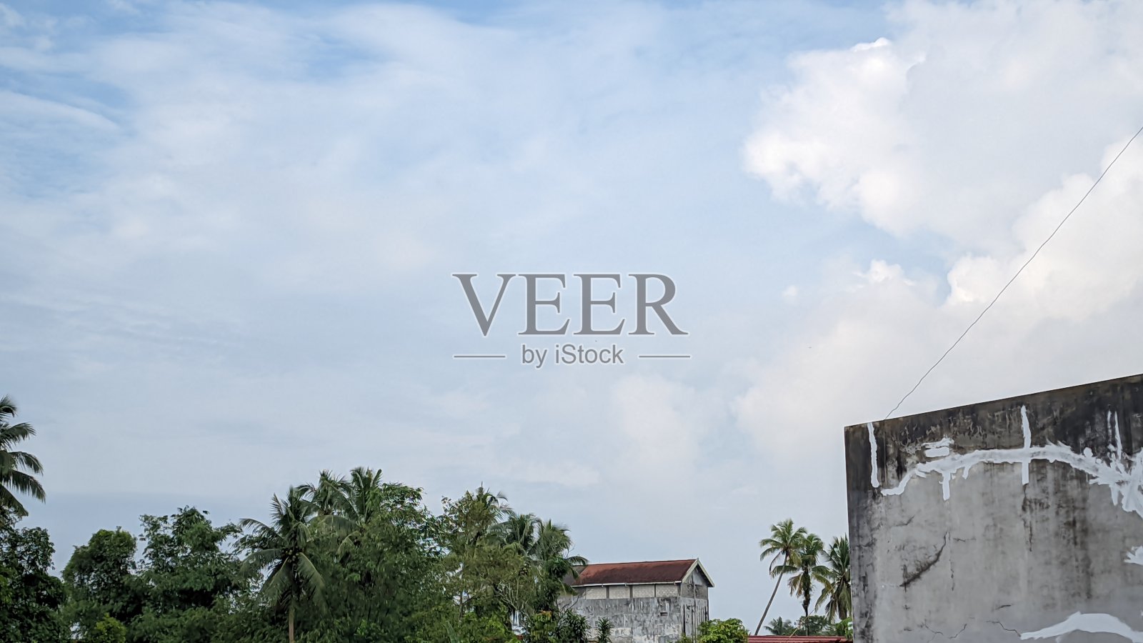 beautiful and cool scenery in the morning in the residential area of ​​Bangka Belitung, blue sky with bright clouds and rows of tropical green trees and roofs of residential buildings照片摄影图片