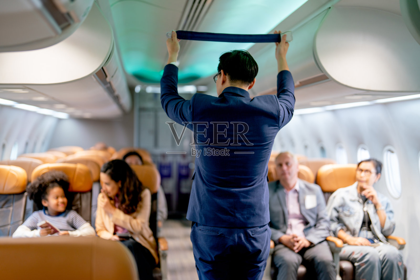 航班起飞前，航空公司工作人员在机场区域向乘客演示和讲解飞机上的安全工具、安全带等。照片摄影图片