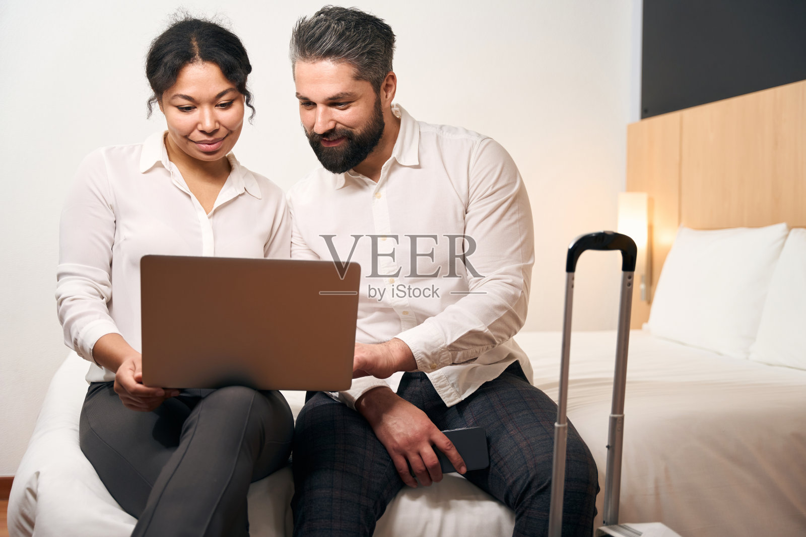 年轻夫妇坐在酒店房间看着电脑显示器照片摄影图片