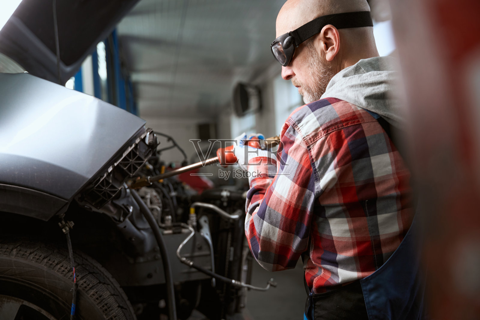 一场事故后，中年男子在车库里修理汽车照片摄影图片