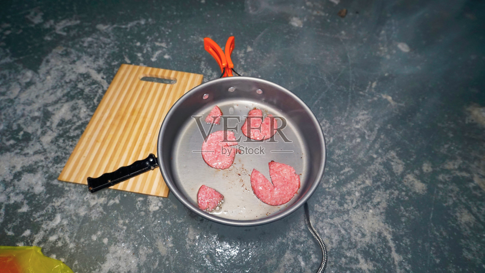 一个人在冰洞里用煤气做饭。照片摄影图片