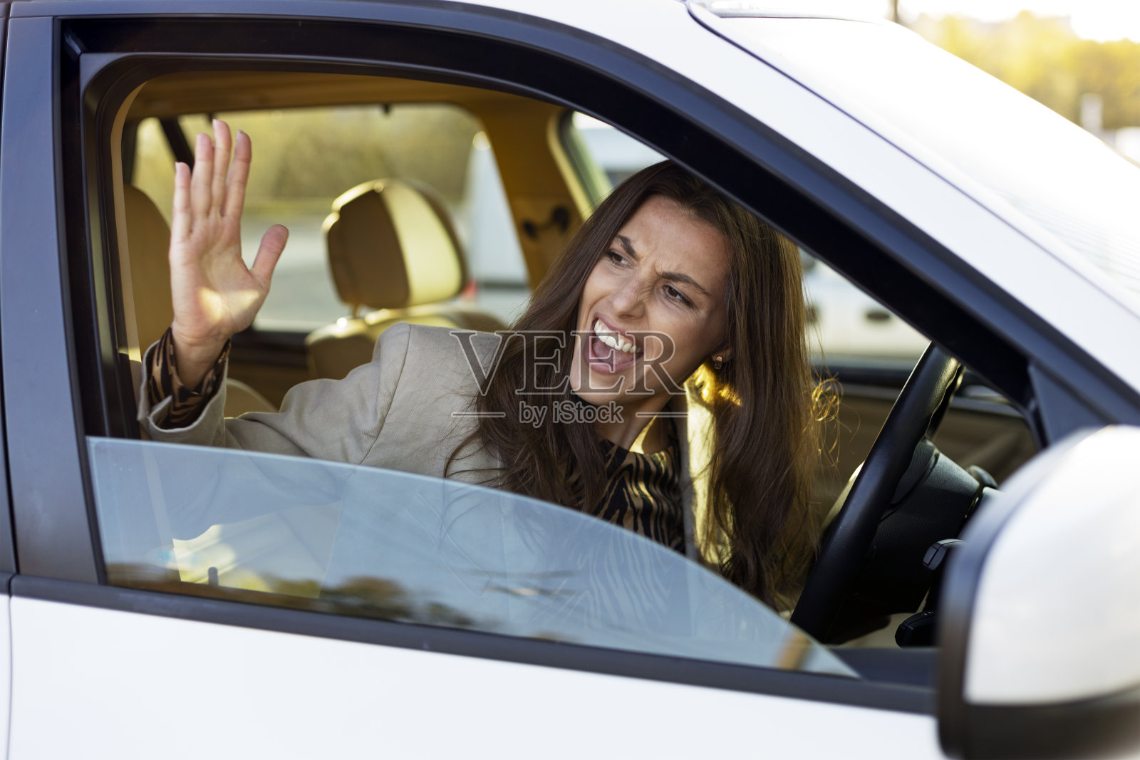 一个迷人的女人在方向盘后面争论，争吵。讨厌的女孩开车。照片摄影图片