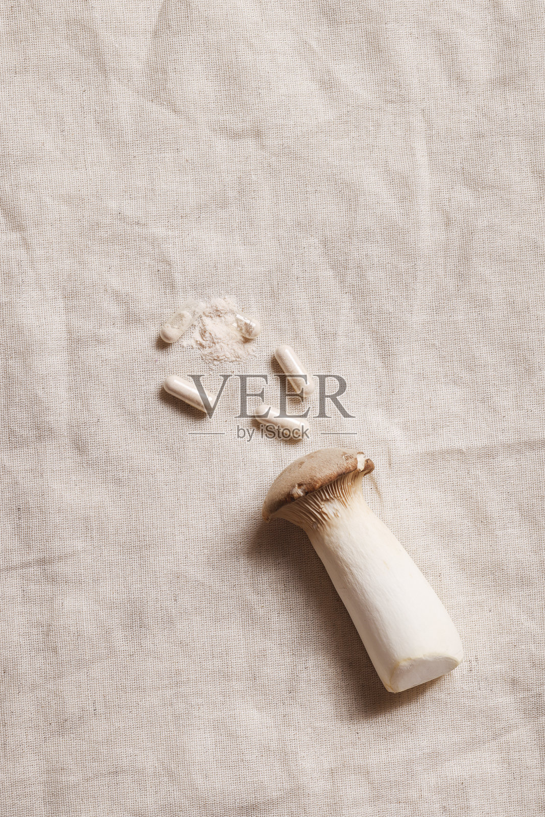 纺织品灰色背景上的蘑菇和天然草药药丸。环保、健康的生活方式、医疗补充理念。副本的空间。照片摄影图片