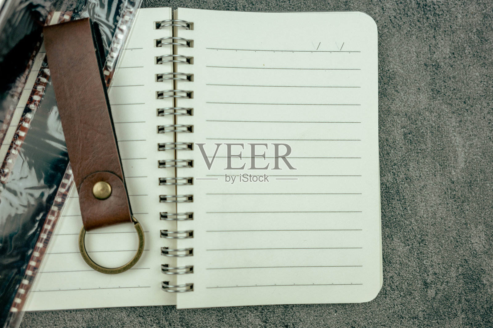 平铺空白笔记本页，打开笔记本用皮革钥匙链和薄膜。照片摄影图片