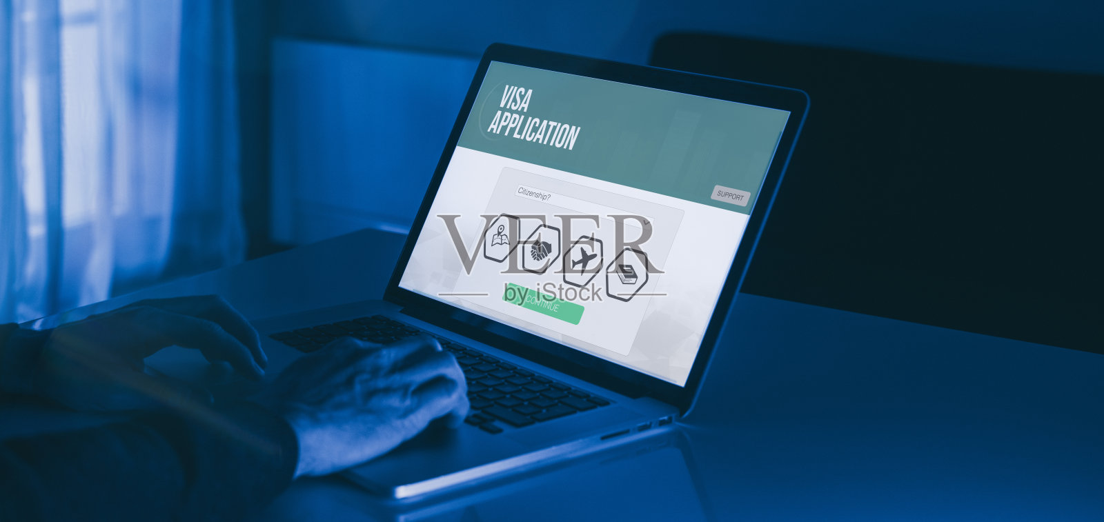 在笔记本电脑上手工填写签证申请表。工作招聘、学习、旅游、移民概念。照片摄影图片