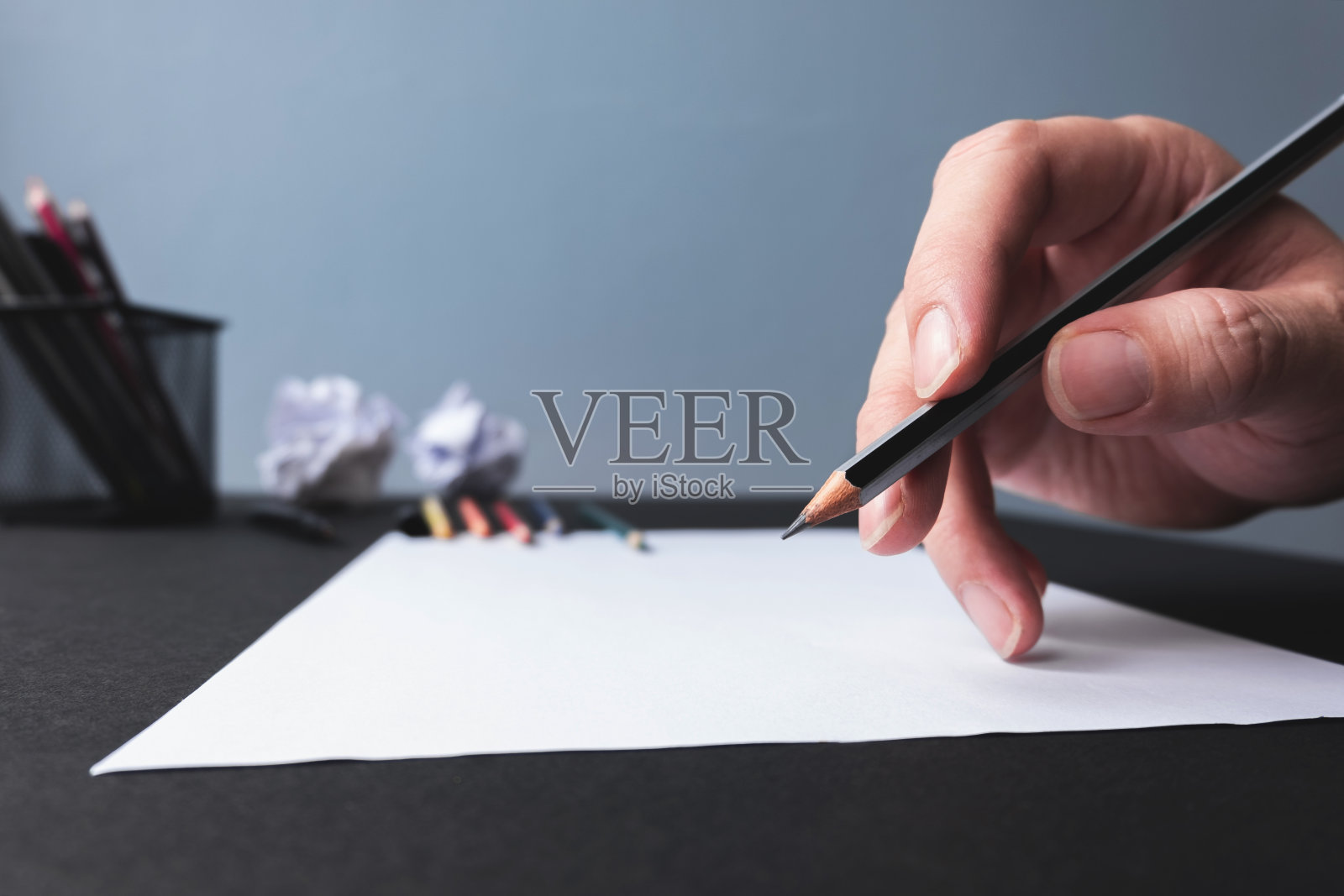 男人开始用铅笔在空白的白纸上画画。照片摄影图片