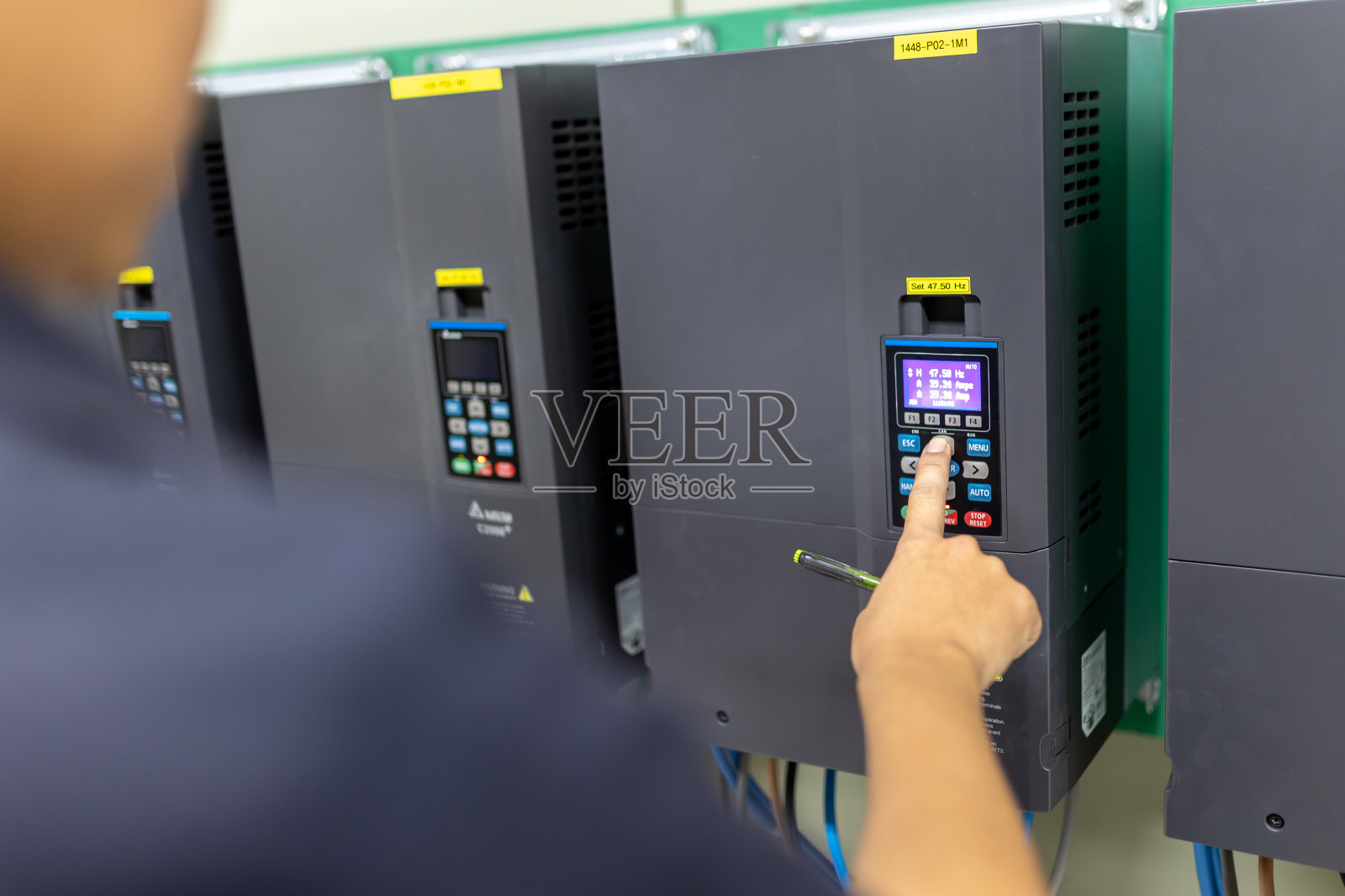 逆变控制室系统电气工程师监测控制器的频率和电流，并将数据记录在手中的纸上。照片摄影图片