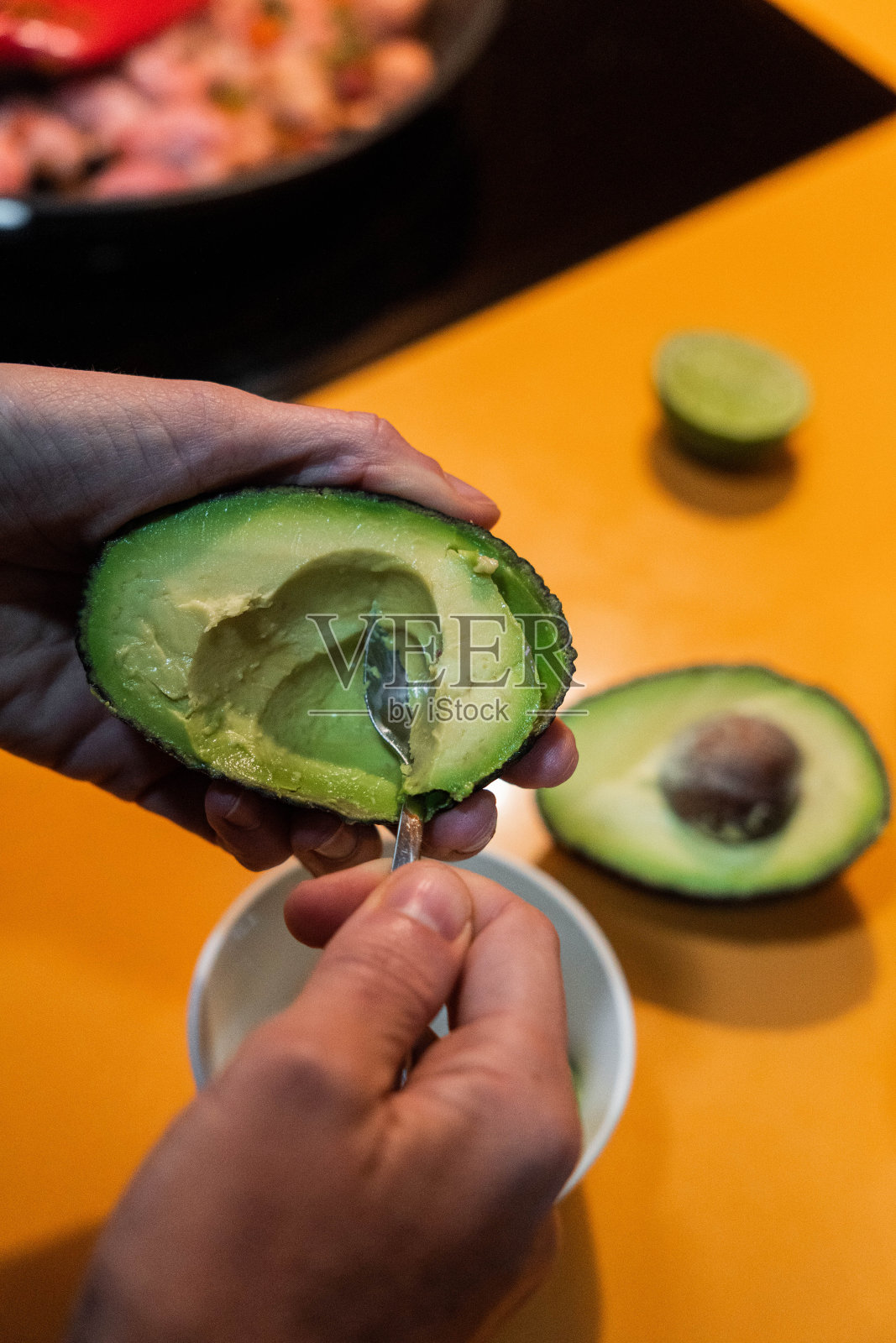 不认识的人用勺子切牛油果。健康的食物照片摄影图片