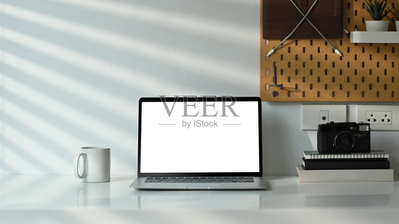 笔记本电脑，空白显示，咖啡杯，相机和书籍在舒适的家木制柜台上。照片摄影图片