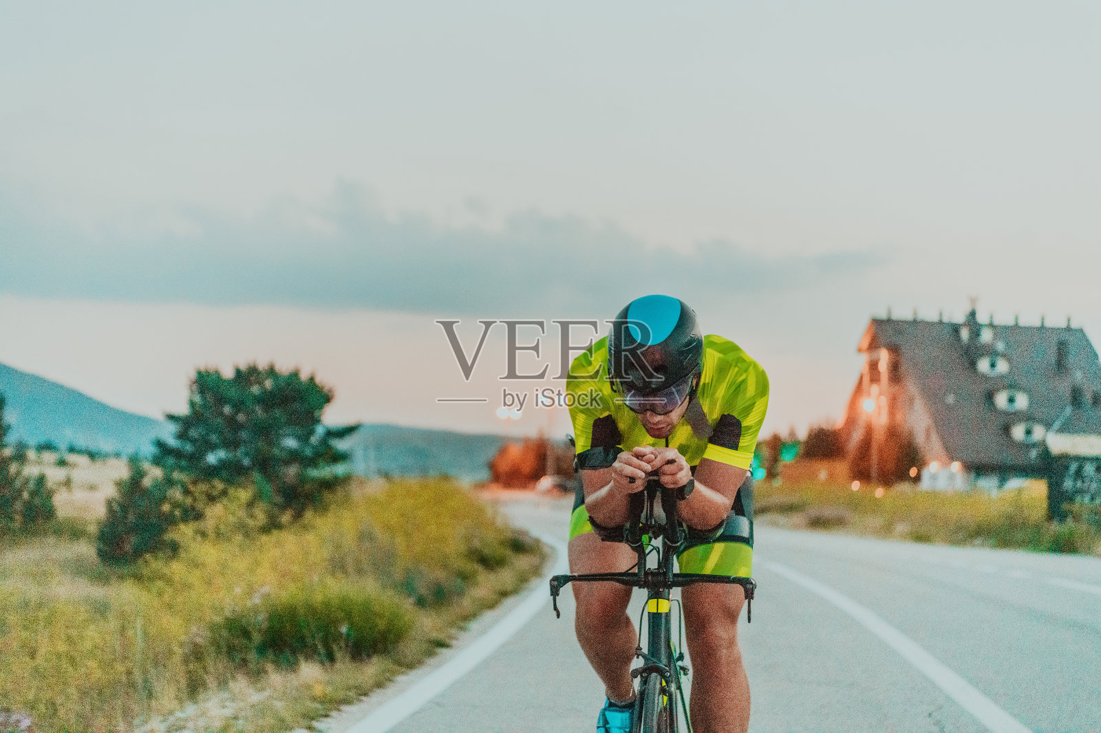 全长肖像一个积极的铁人三项运动员在运动服和一个保护头盔骑自行车。有选择性的重点照片摄影图片