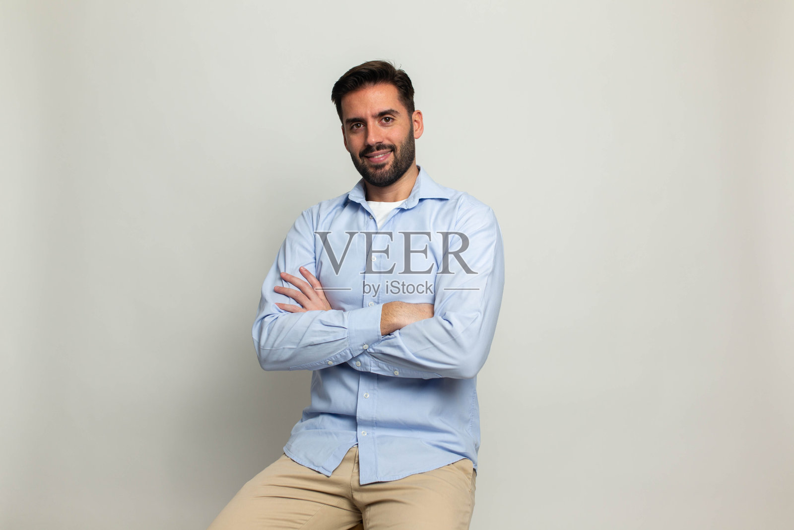 年轻英俊的商人穿着休闲牛仔衬衫，手腕上戴着智能手表，孤立在灰色背景上照片摄影图片