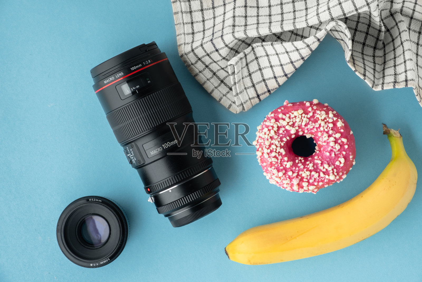 俯视图的香蕉，甜甜圈与粉红色巧克力糖衣和微距镜头在蓝色背景。美食摄影和造型概念。平的。照片摄影图片