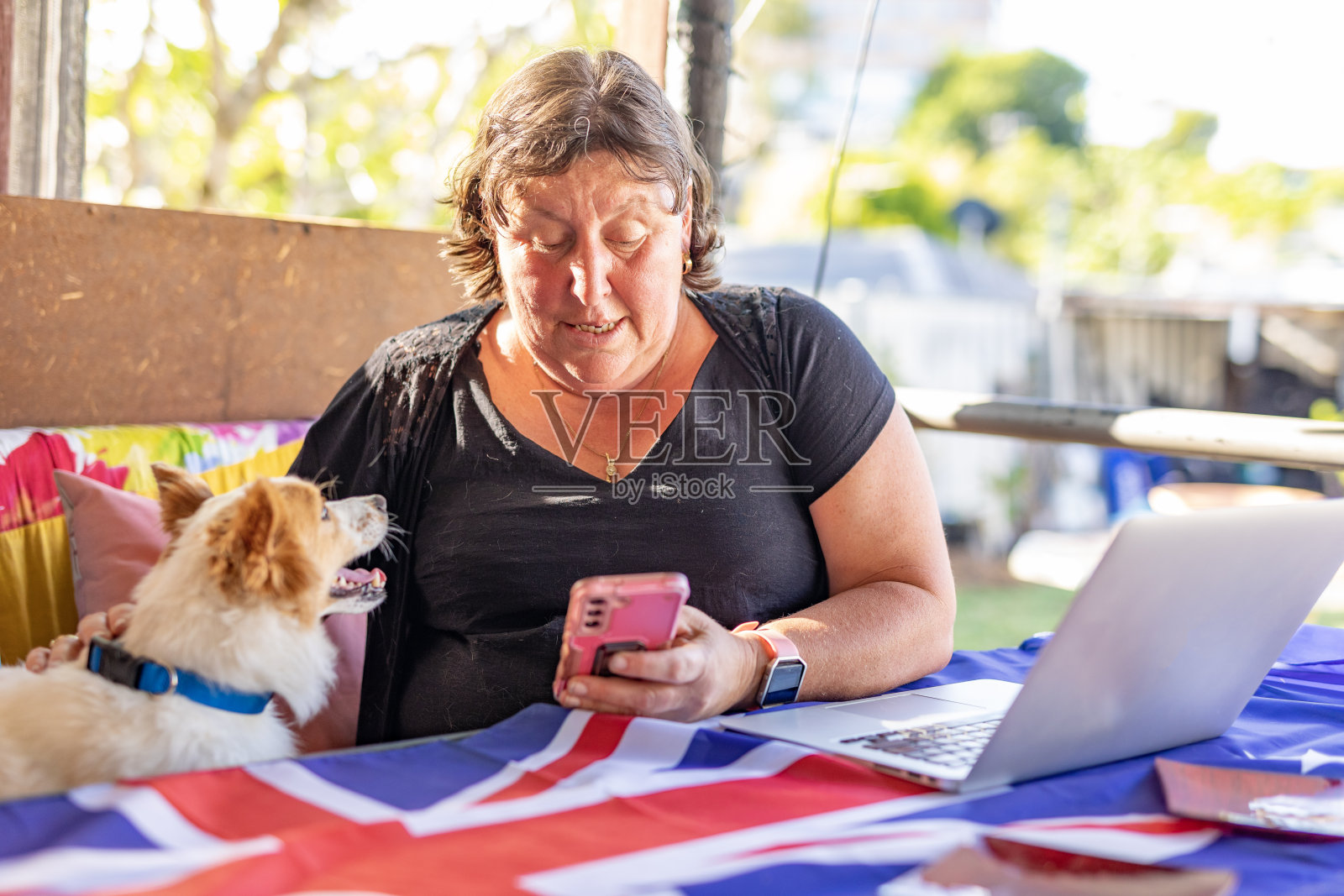 快乐的成熟女人和她的狗一起用手机照片摄影图片