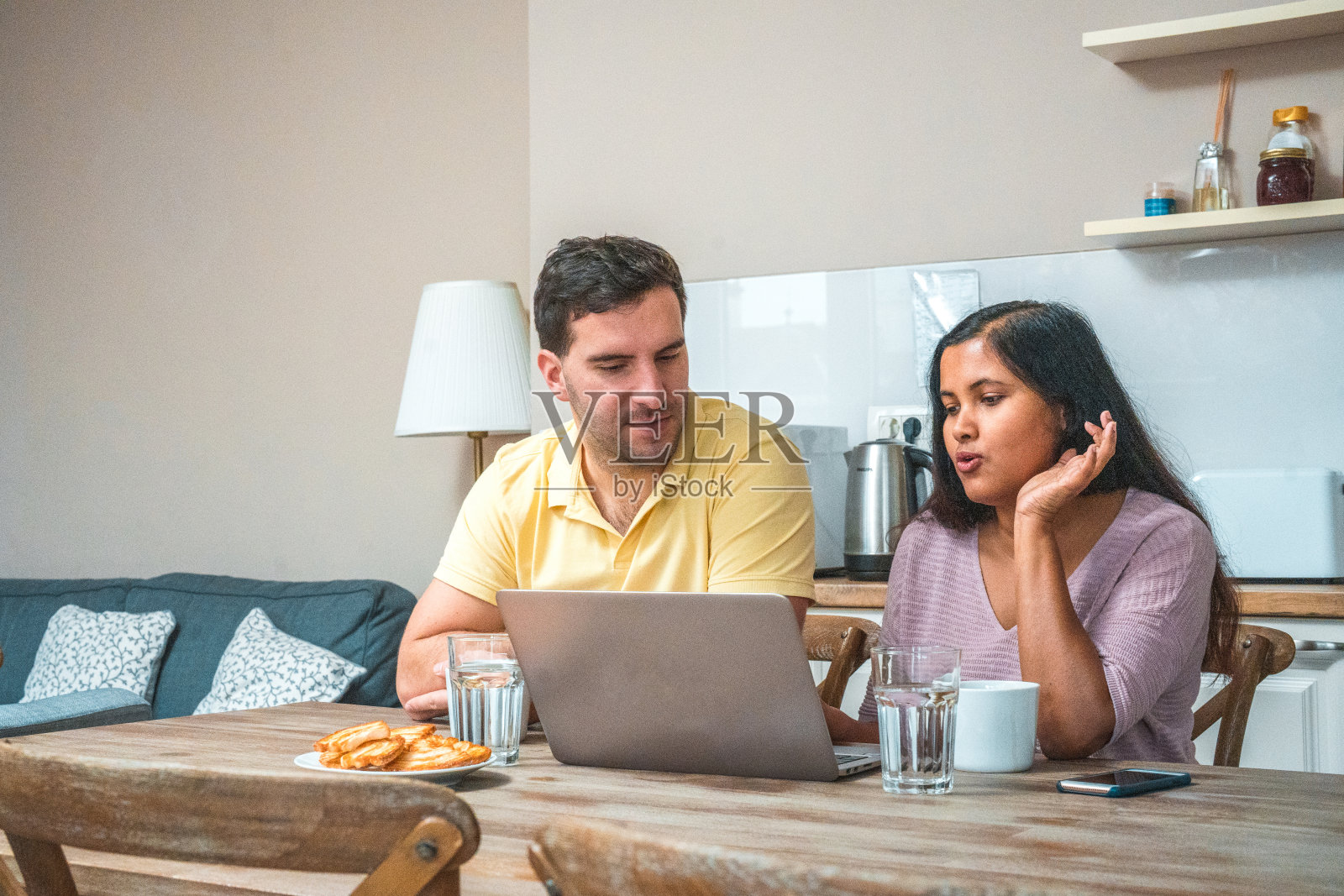 不同的夫妇在厨房里用笔记本电脑娱乐自己照片摄影图片