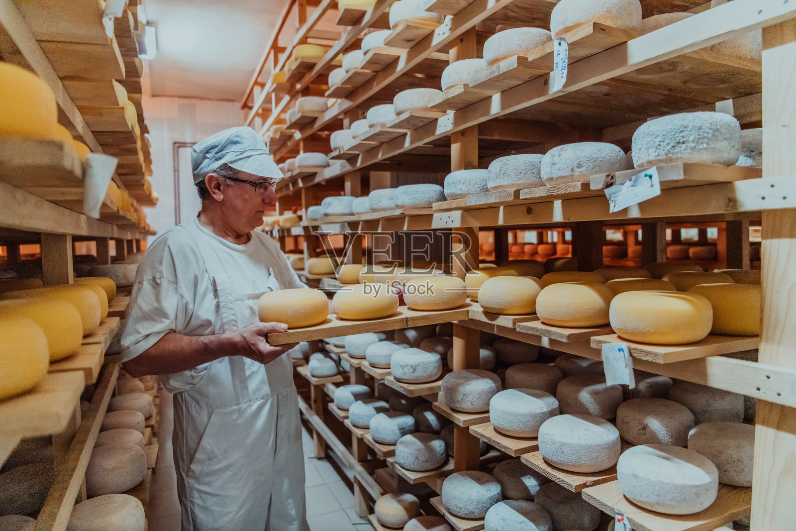 一名奶酪工厂的工人在干燥的架子上分类新鲜加工的奶酪照片摄影图片