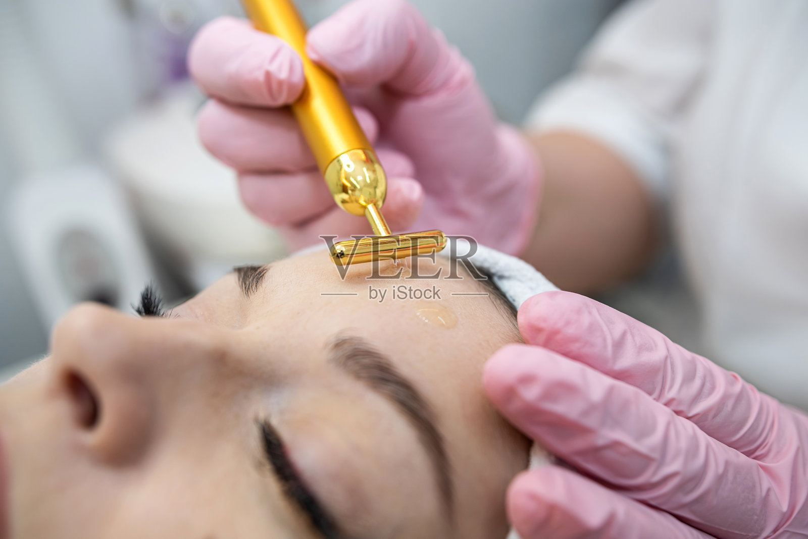 妇女接受程序，在脸上的金脉冲面部按摩器照片摄影图片