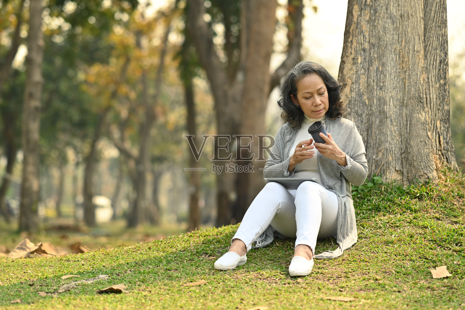 愉快的中年妇女喝咖啡，在美丽的花园背景下放松。照片摄影图片
