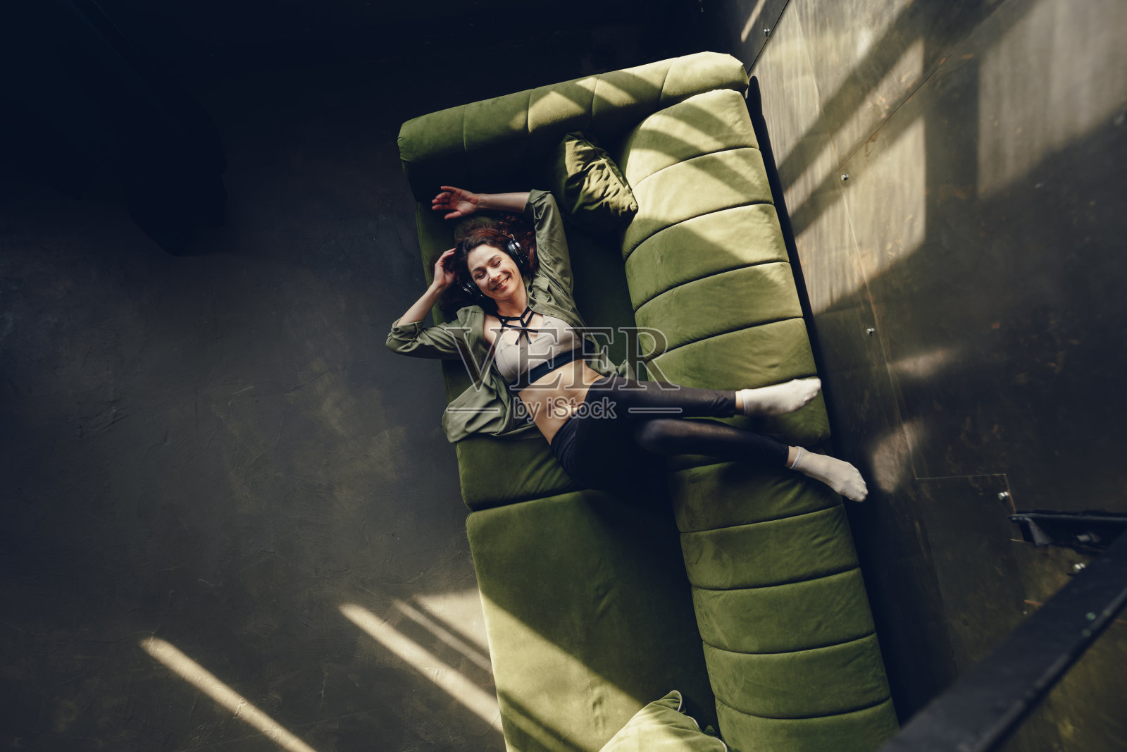 快乐的年轻女子戴着耳机躺在沙发上照片摄影图片