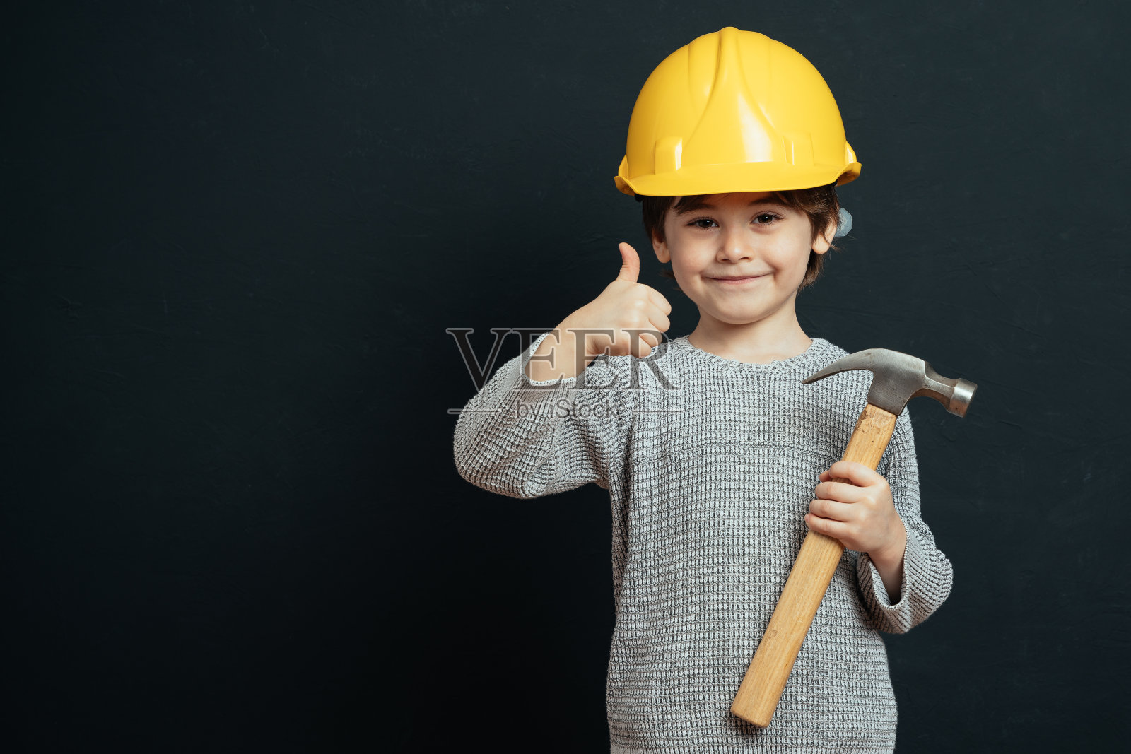 小工作男孩的肖像，戴着黄色安全帽照片摄影图片