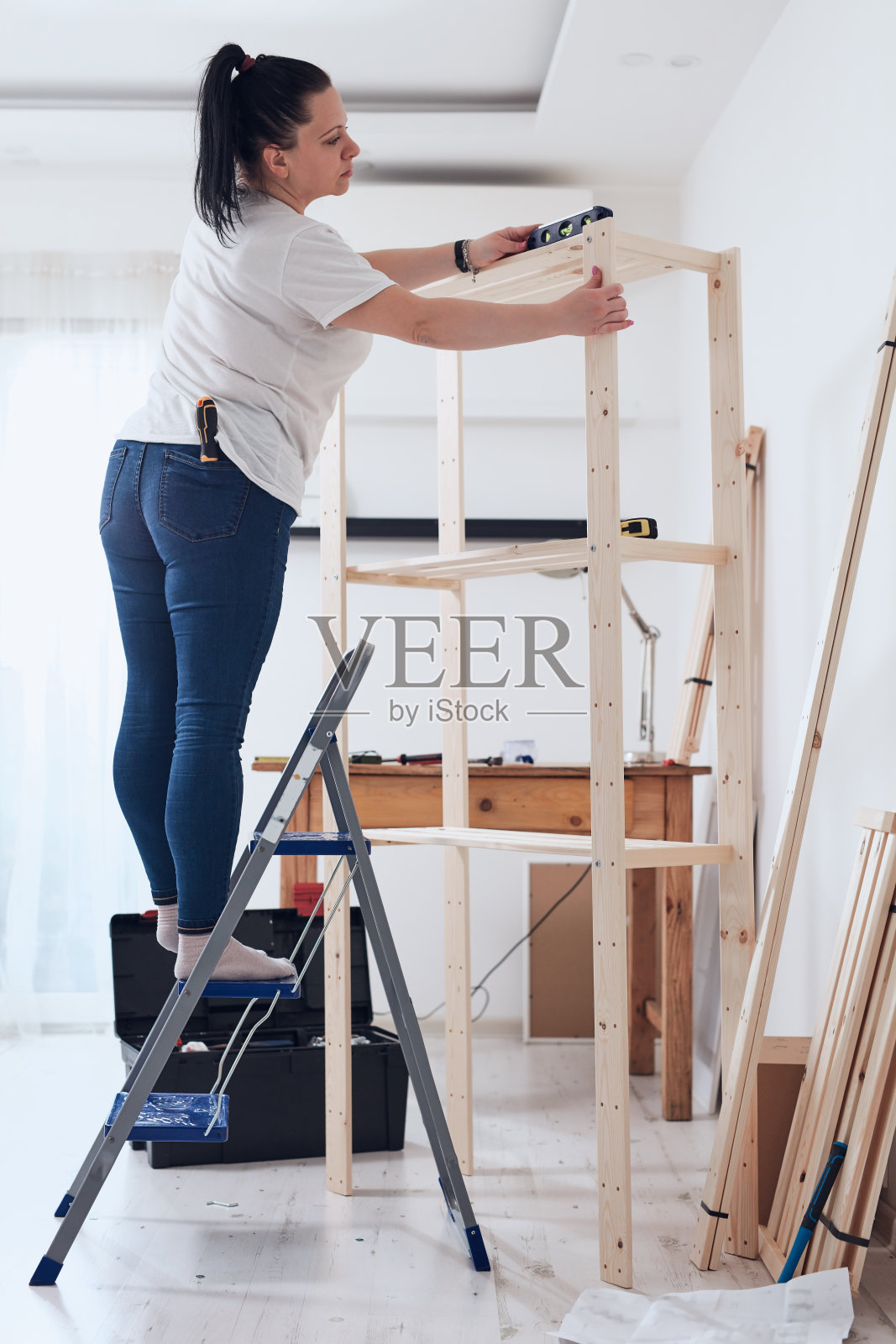 在公寓里组装新木架和家具的女人。照片摄影图片