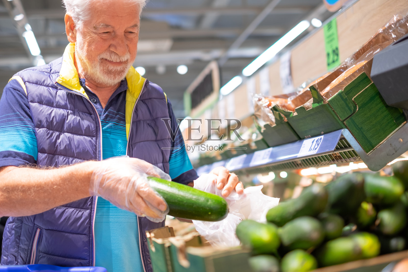 白发老人在超市里选购杂货，挑选蔬菜，小心翼翼地考虑成本——消费主义的概念，价格上涨，通货膨胀照片摄影图片