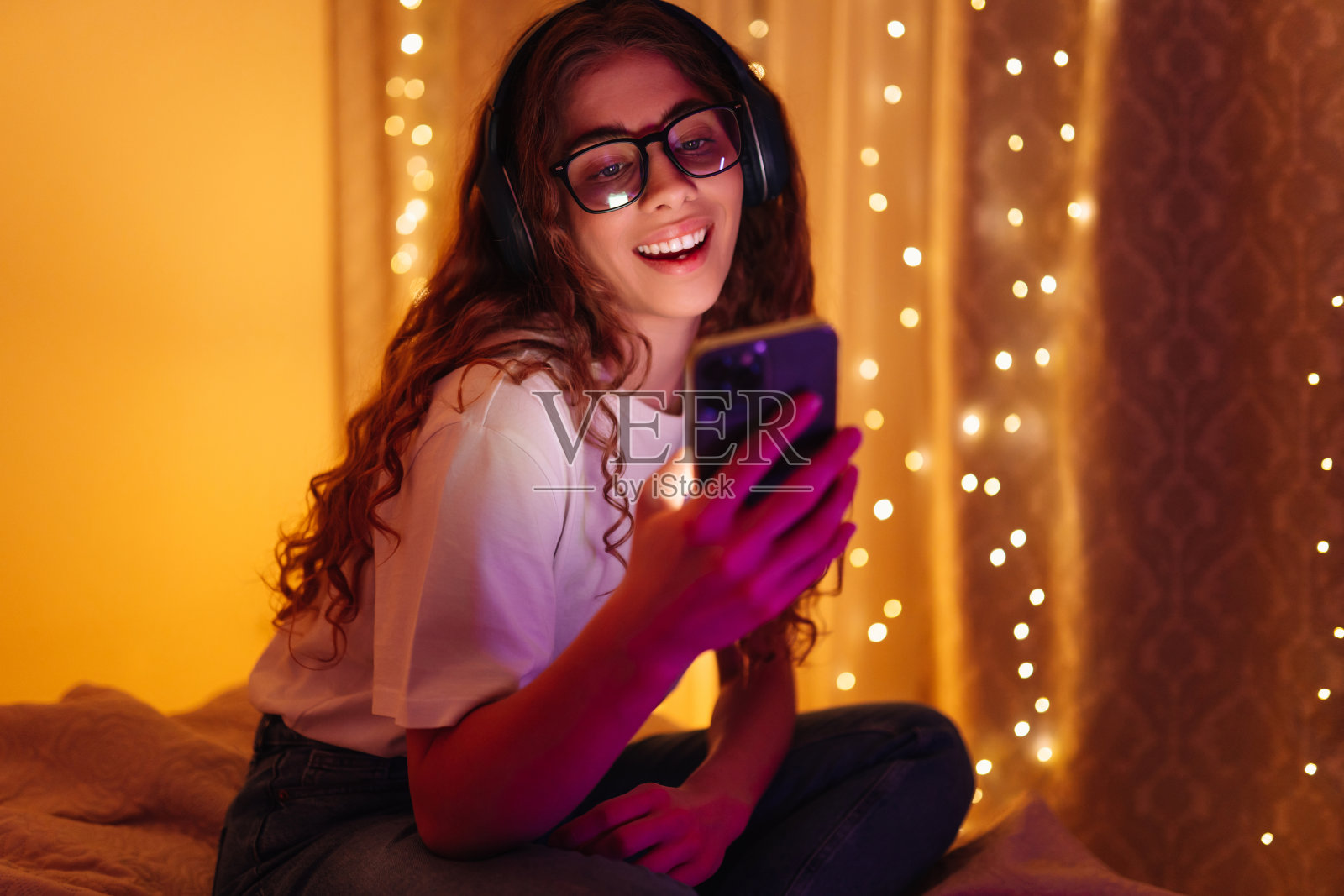 年轻女子戴着耳机听音乐聊天。照片摄影图片