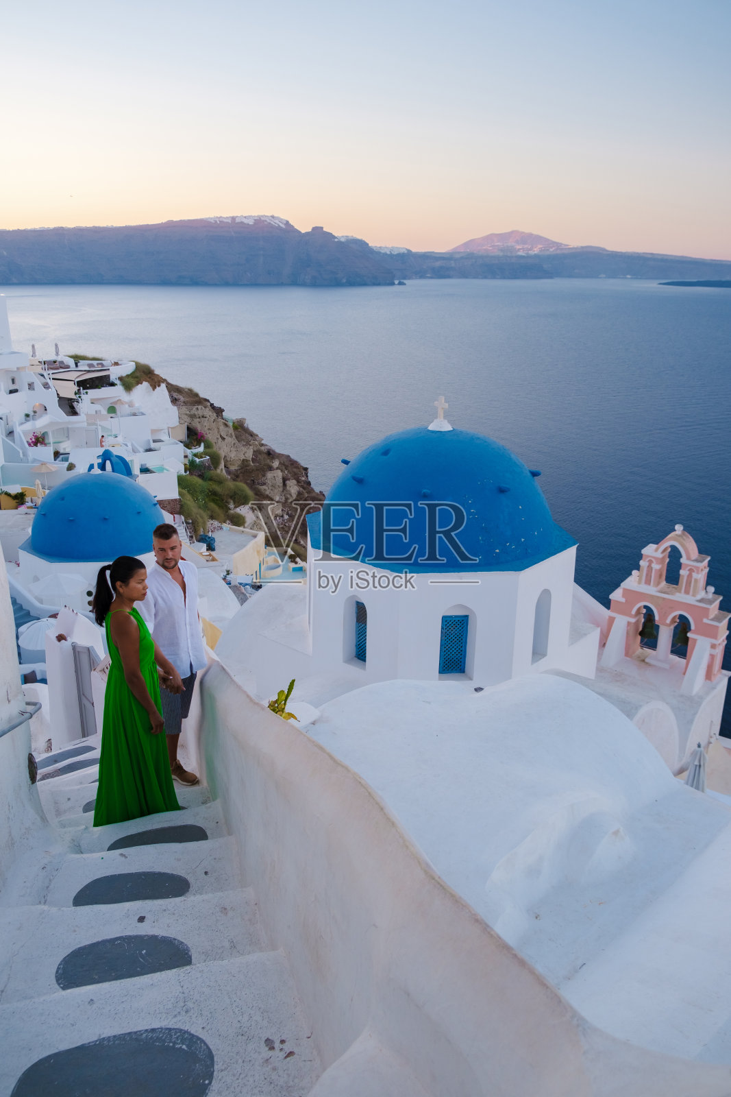 情侣参观希腊圣托里尼岛，男人和女人参观粉刷成白色的希腊村庄伊亚照片摄影图片