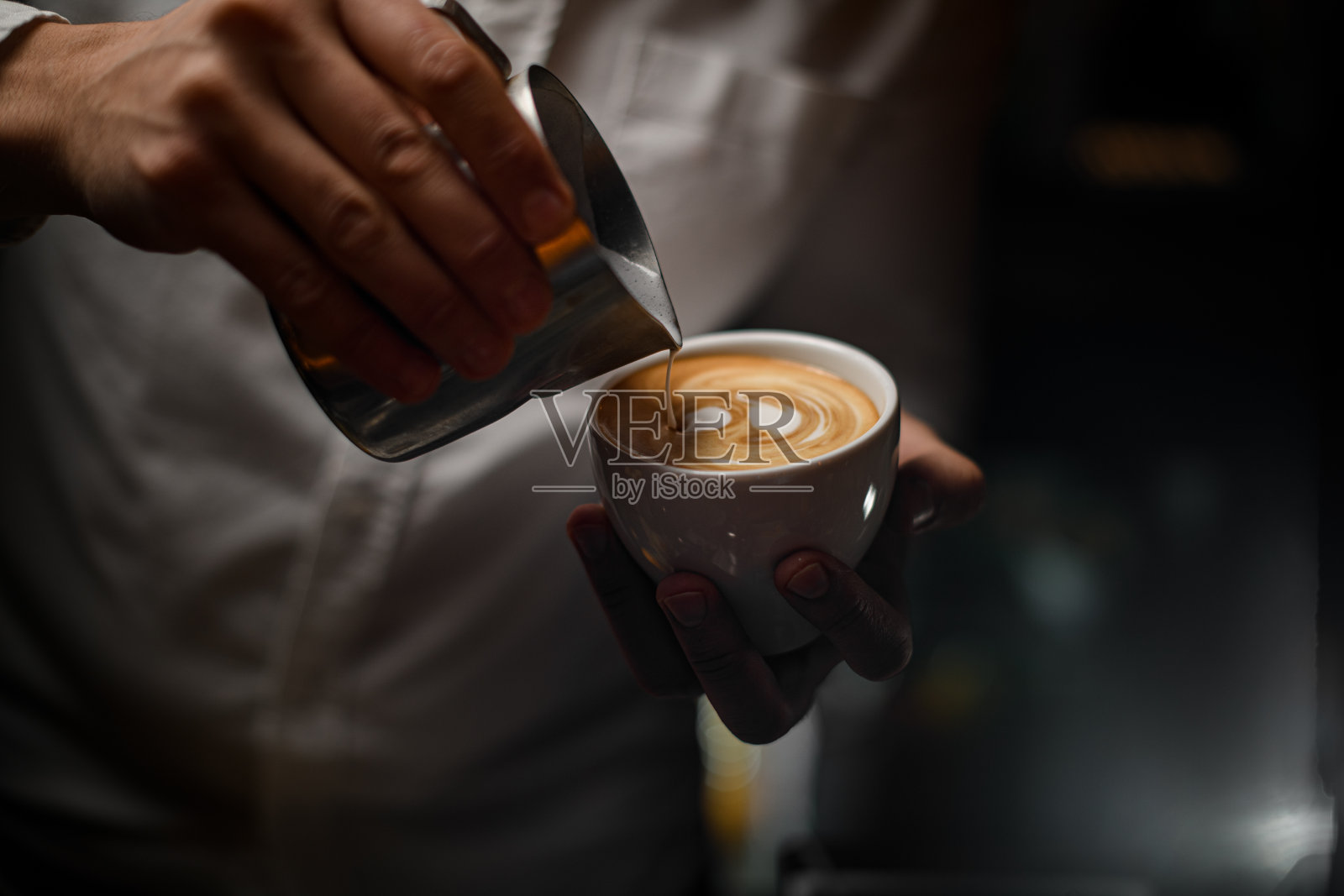 从钢壶中将鲜奶油倒入咖啡杯的过程观察照片摄影图片