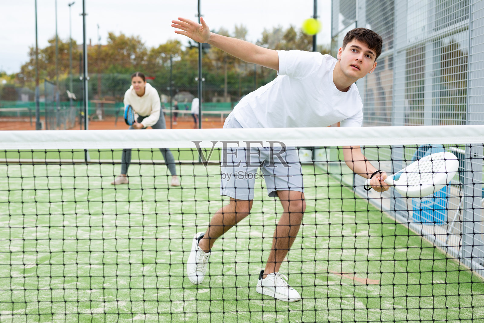 在训练期间，一名男子穿着运动服在球场上玩平板网球比赛照片摄影图片