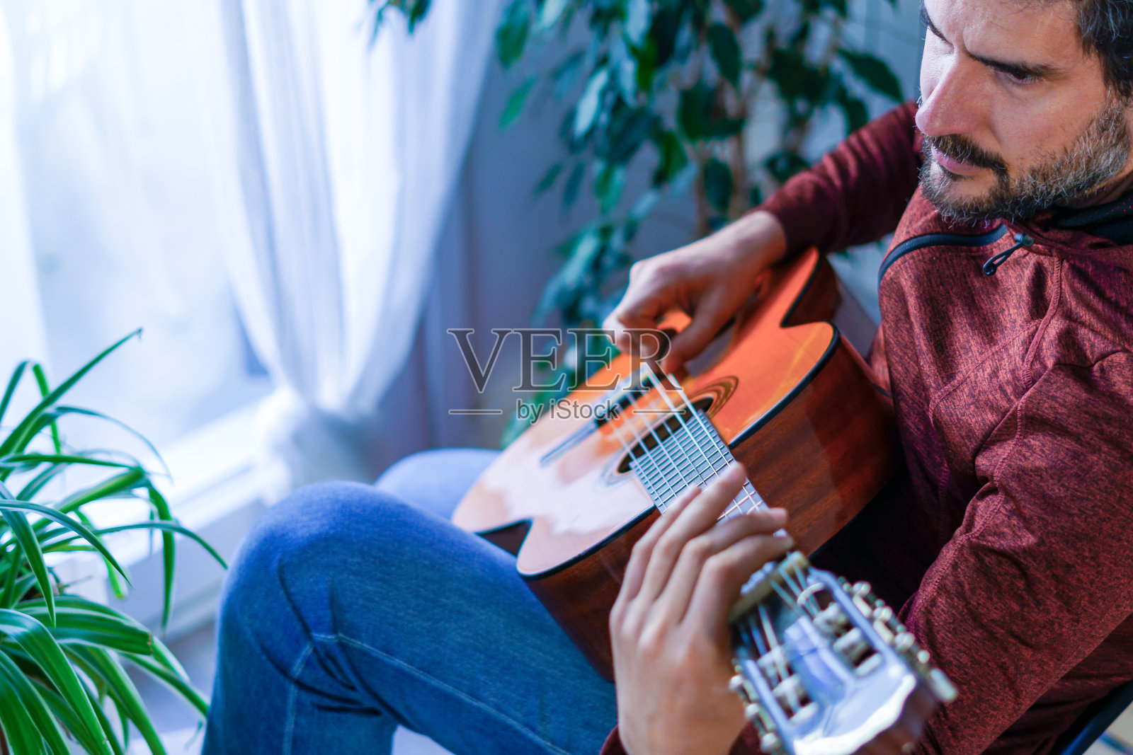 一个坐在椅子上弹西班牙吉他的人照片摄影图片