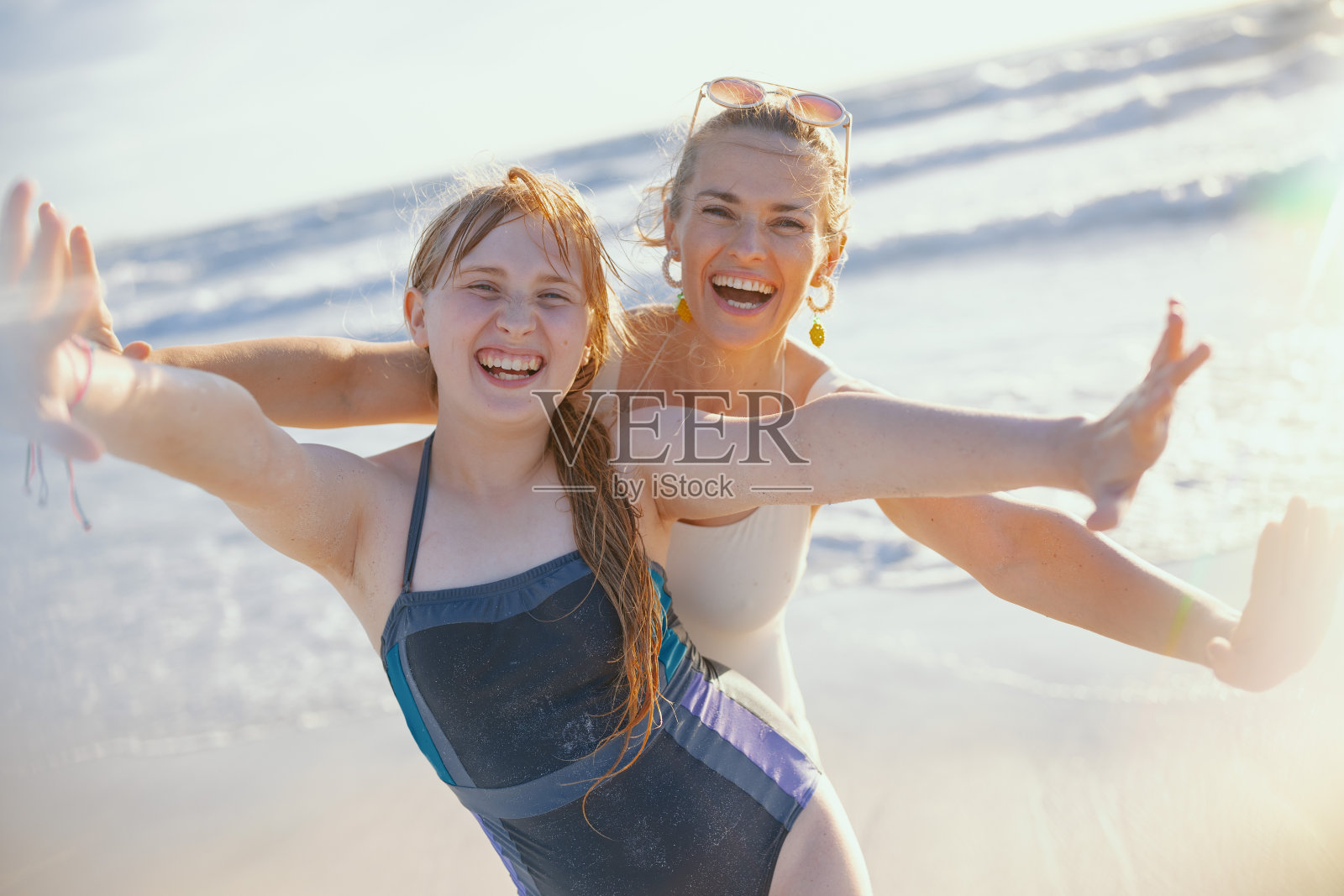 微笑的母亲和十几岁的女儿在海滩上玩得很开心照片摄影图片