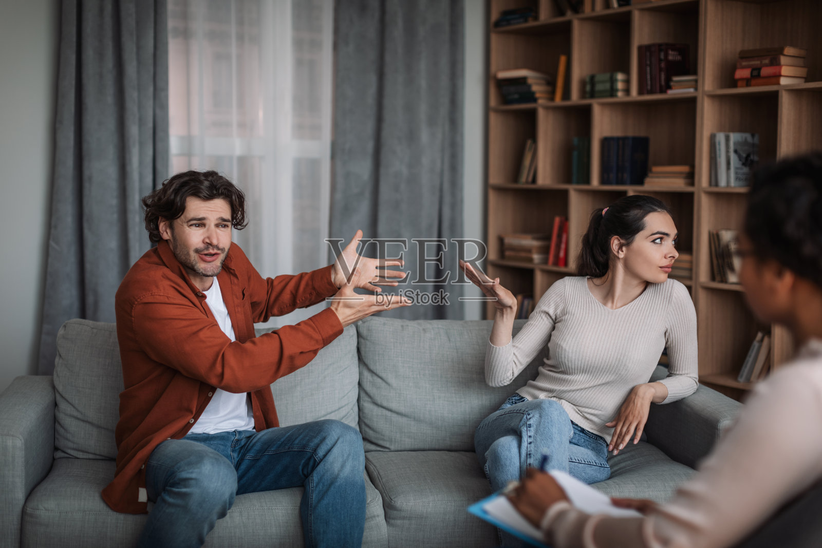 在诊所内部进行家庭咨询时，愤怒兴奋的年轻欧洲男子咒骂妻子照片摄影图片