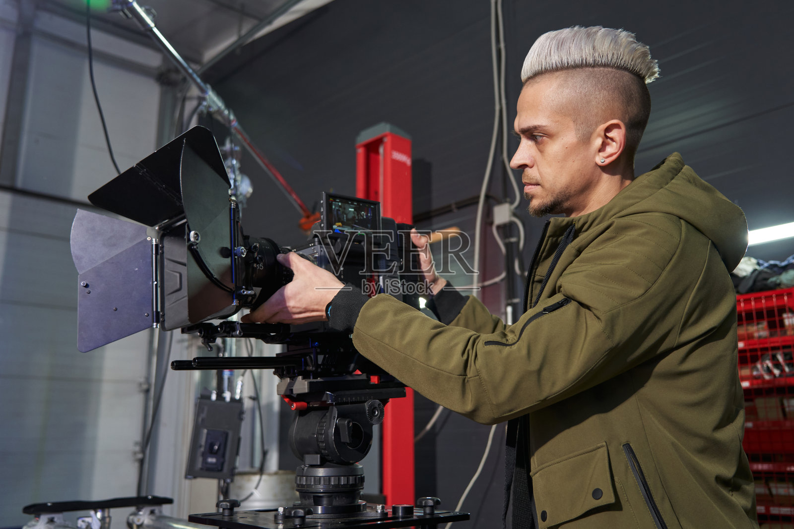 高加索摄影师与头发调整聚焦在专业的电影相机在设置照片摄影图片