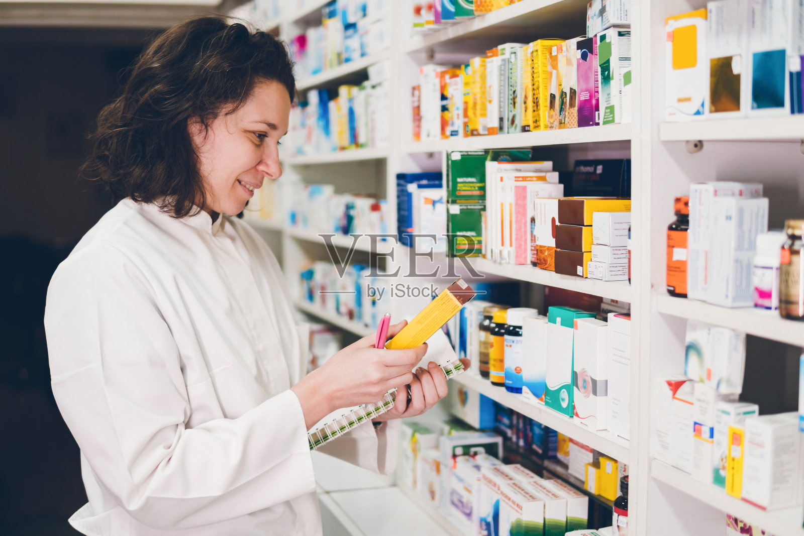 一位年轻的女药剂师在药店的货架上整理药品照片摄影图片