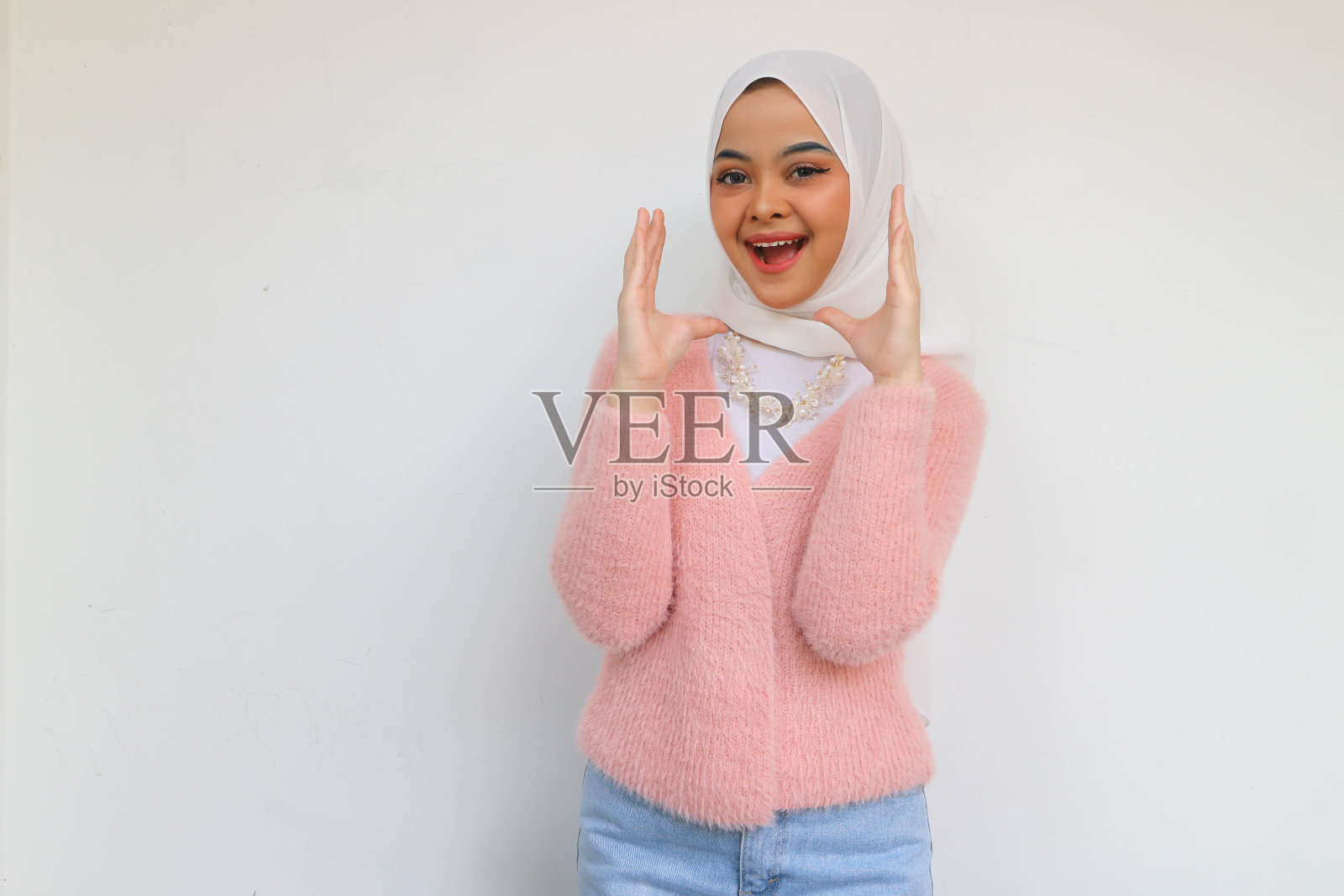 欢呼的亚洲年轻女子希贾布穿着粉红色的运动上衣，大喊大叫，看起来自信的相机孤立在白色背景照片摄影图片