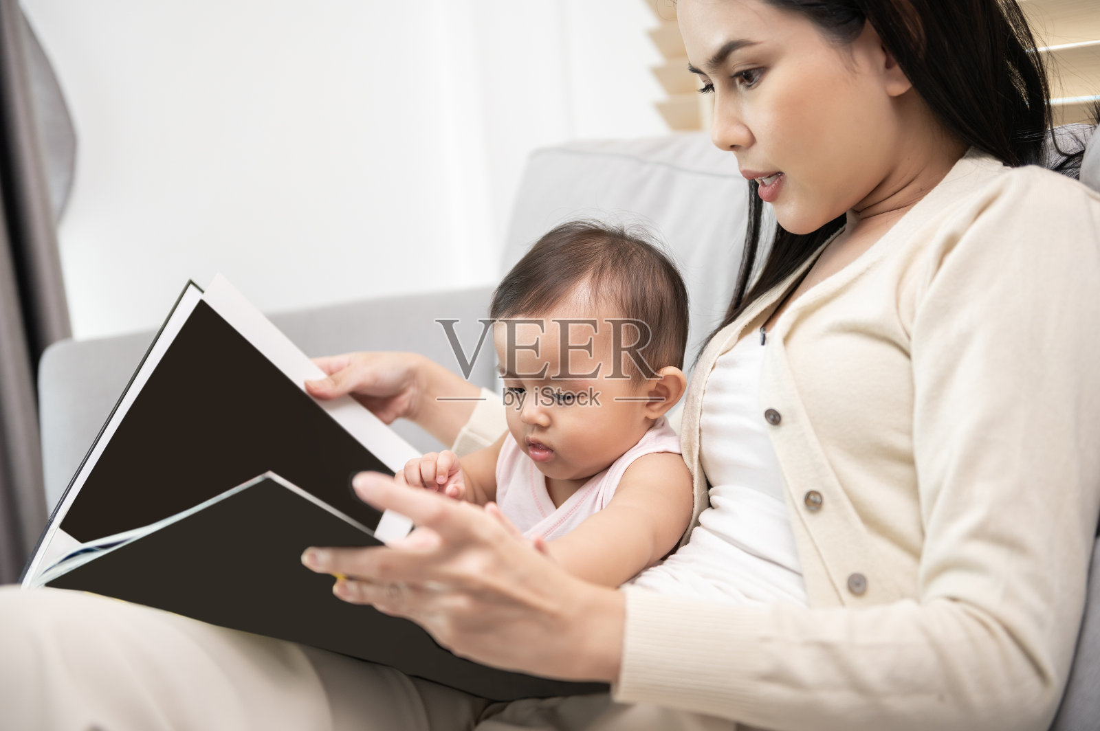 美丽的妈妈在家里给女儿读书照片摄影图片