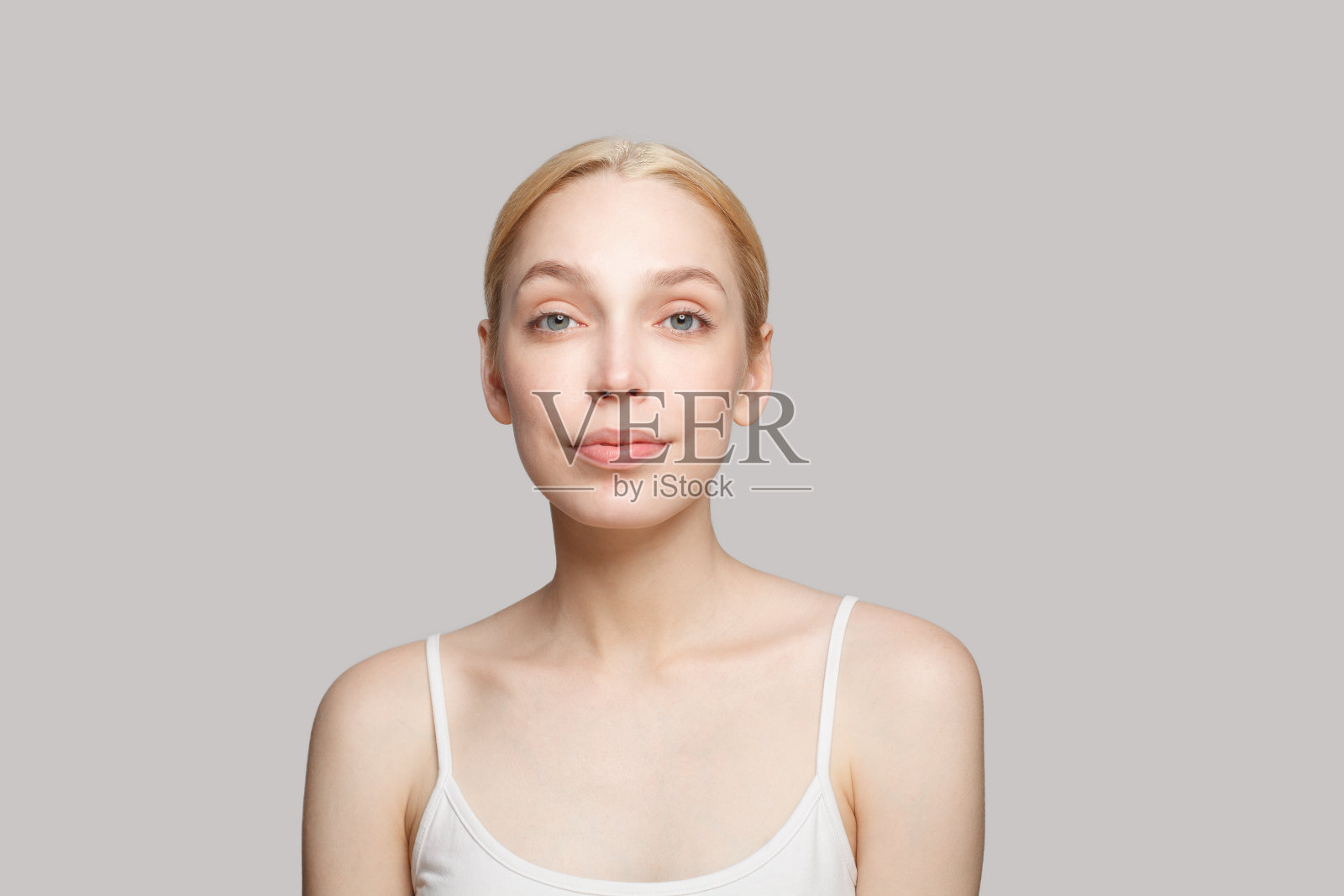 快乐的女人在白色背心微笑孤立的灰色背景。美容、化妆品、护肤、魅力照片摄影图片