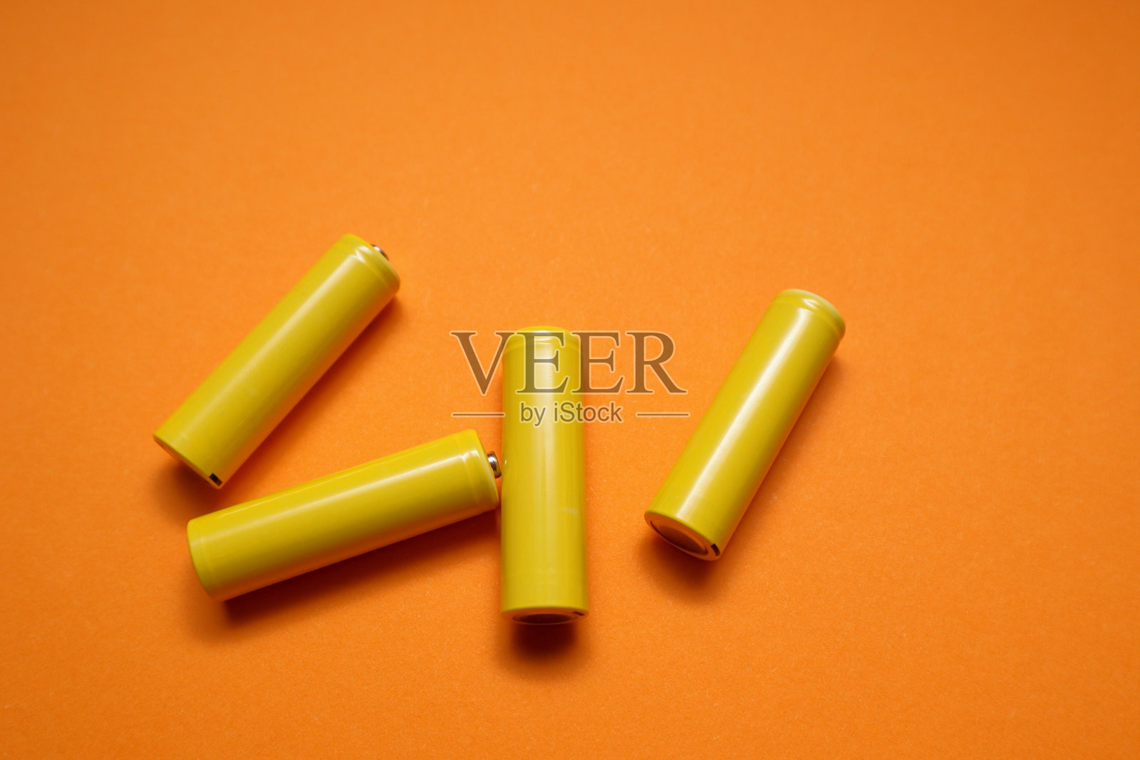 AA充电电池在橙色与剪辑路径。黄色电池在黄色粉彩背景照片摄影图片