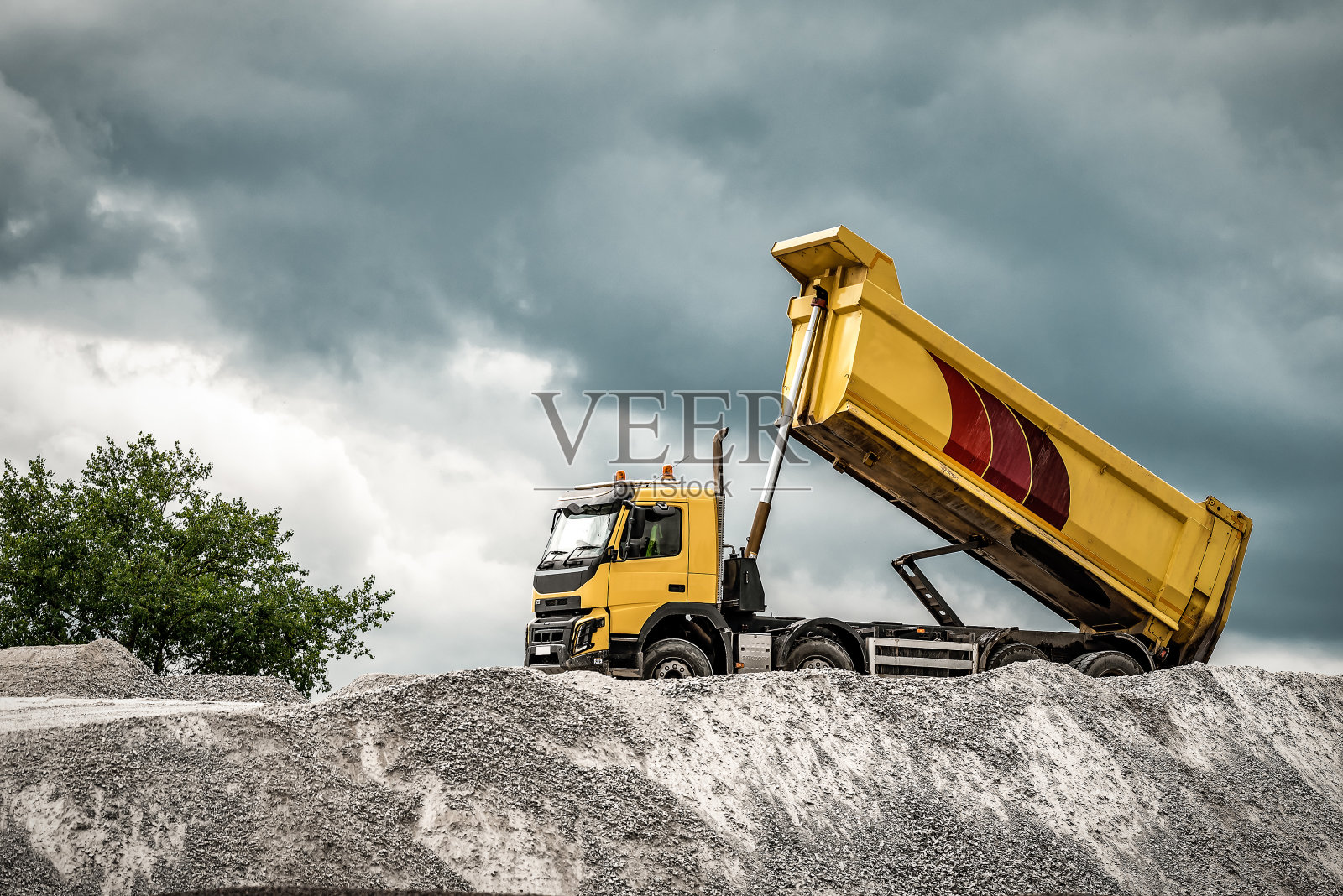 一辆大型矿用卡车把砾石卸下来。一个凸起的土壤运输车倾倒土壤。照片摄影图片