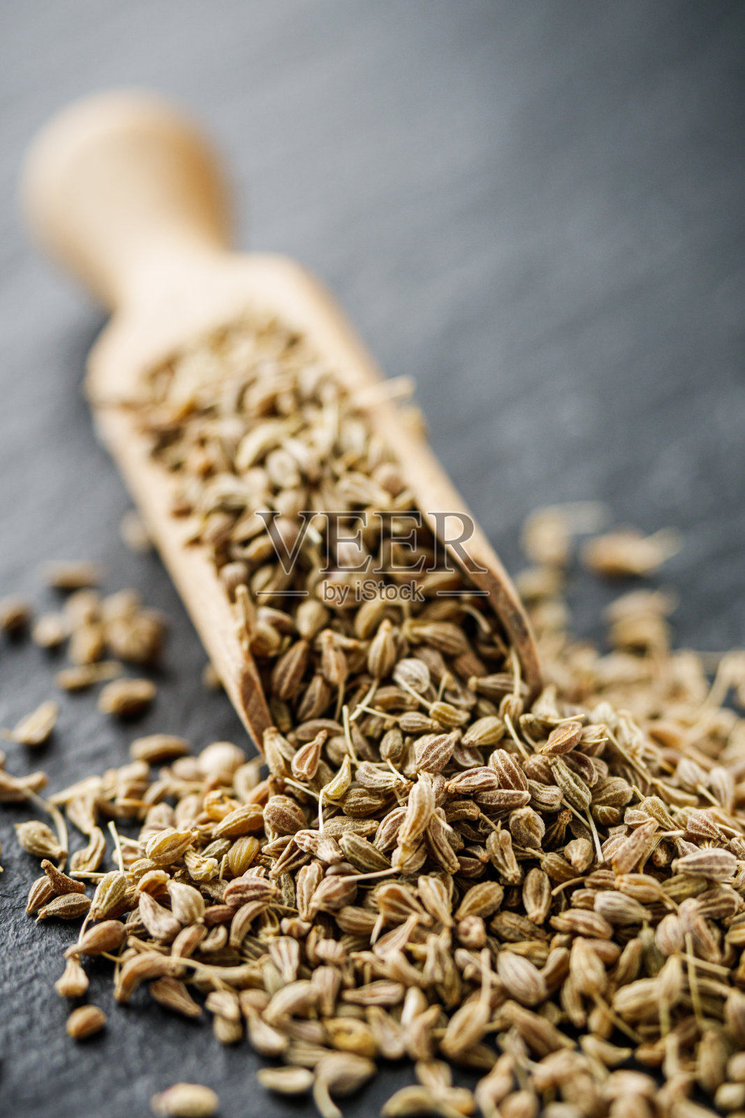 芳香的干茴香种子在深黑色的石头背景照片摄影图片