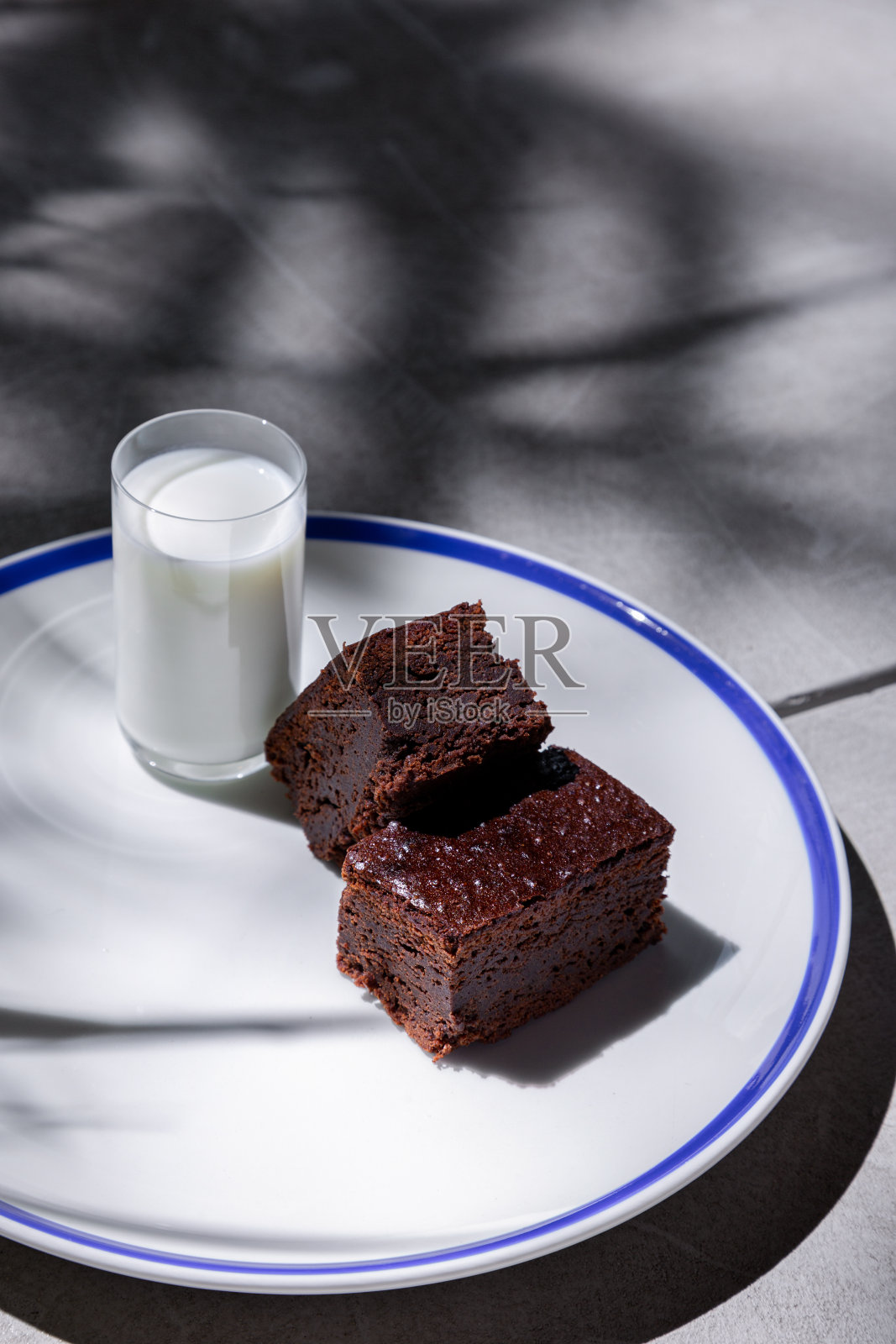 水泥桌子上的盘子里有几块巧克力派和一杯小牛排照片摄影图片