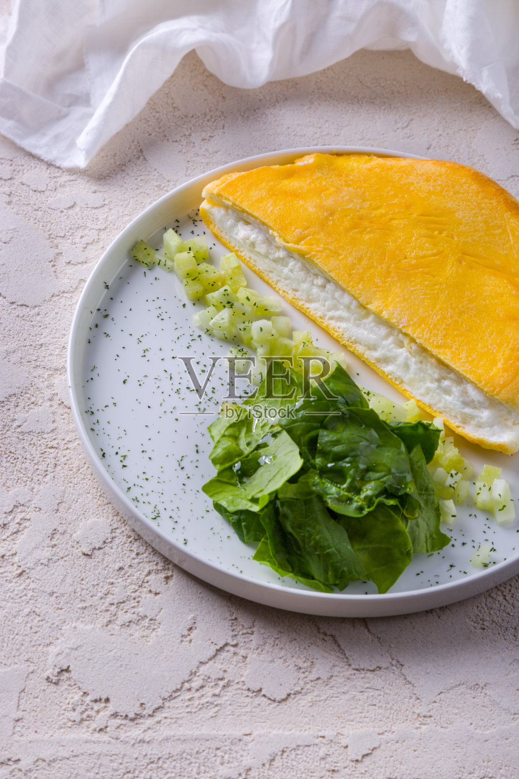 芝士蛋糕配黄瓜片、罗勒和酱汁，盘子放在粗糙的混凝土上，背景是一块布照片摄影图片